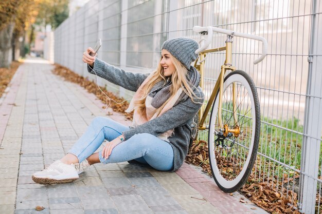 Femme prenant selfie près de vélo et clôture