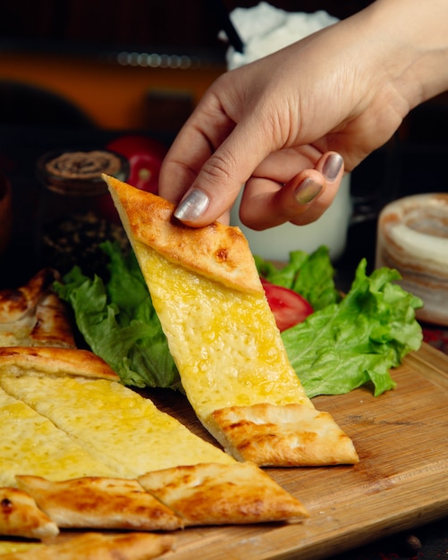 Photo gratuite femme prenant une tranche de pain à la turque avec du fromage fondu.