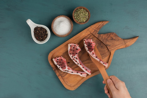 Une femme prend un morceau de viande non cuite sur une planche de bois.