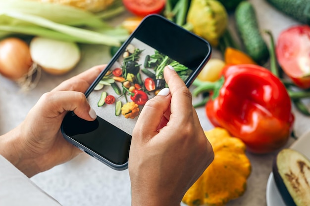 Une femme prend une photo de légumes sur un smartphone