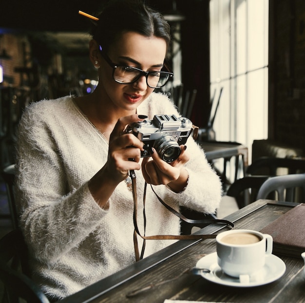 Photo gratuite femme prend une photo sur photocamera rétro assis dans le café