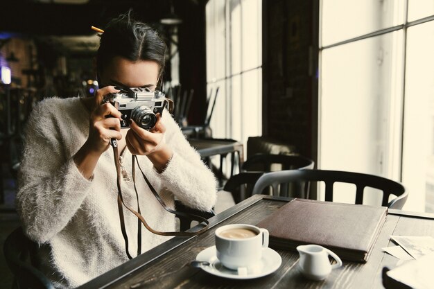 Femme prend une photo sur photocamera rétro assis dans le café