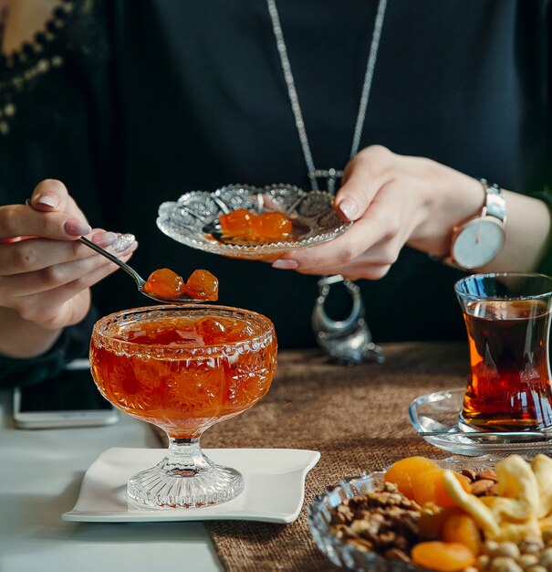 Femme, prendre, confiture cerise, depuis, cristal, verre, bol, boire, thé noir