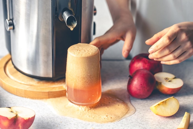 Photo gratuite une femme prépare du jus de pomme à la maison avec une centrifugeuse