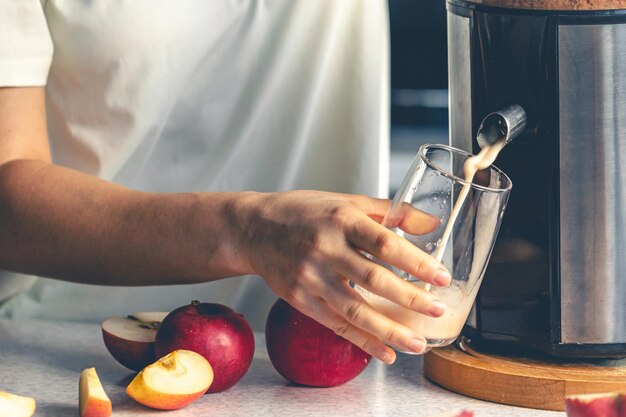 Photo gratuite une femme prépare du jus de pomme à la maison avec une centrifugeuse