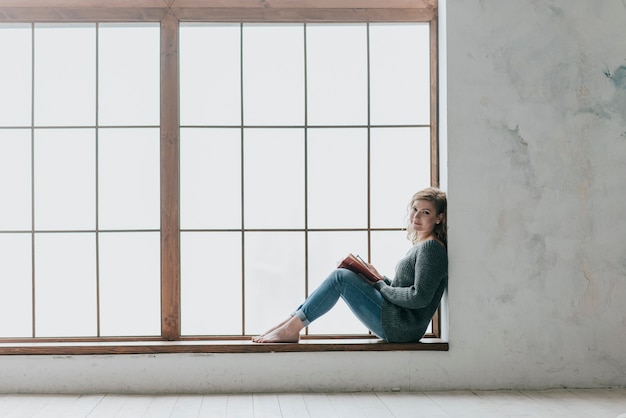 Photo gratuite femme près de la grande fenêtre en regardant la caméra