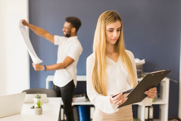 Femme avec le presse-papier au bureau