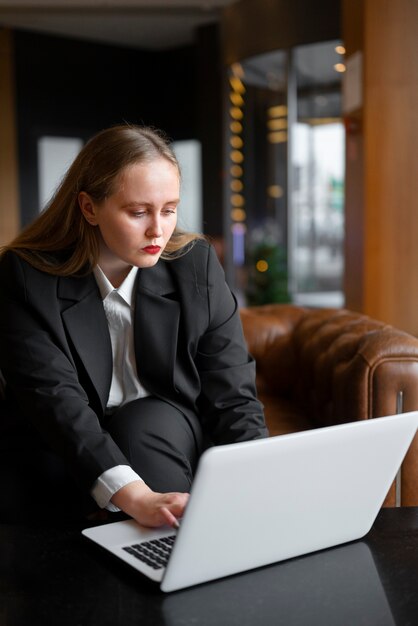 Femme professionnelle en costume élégant au bureau avec ordinateur portable