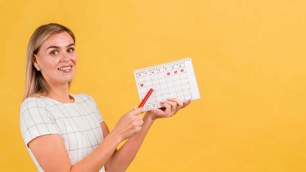 Femme de profil montrant son calendrier de menstruation