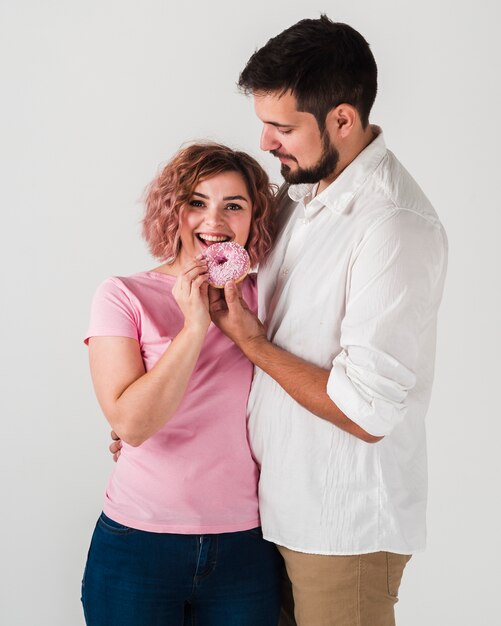 Femme profitant d'un beignet et posant avec un homme