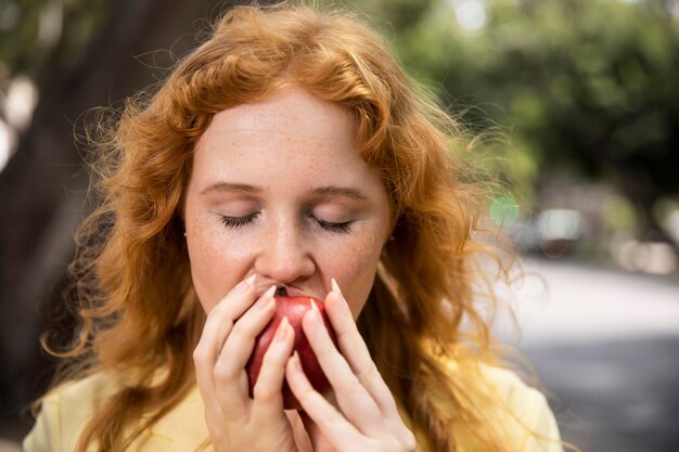 Photo gratuite femme profitant d'une pomme à l'extérieur