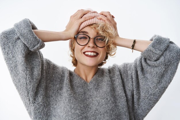 Femme profitant de vacances dans les montagnes enneigées debout ravi et joyeux touchant le bonnet sur la tête souriant largement et debout satisfait