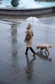 Femme promenant son chien dans la ville pendant qu'il pleut