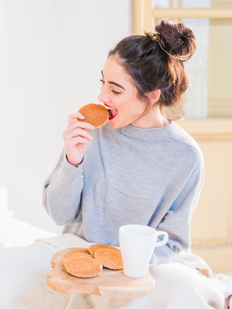 Femme, pull gris, manger, biscuits