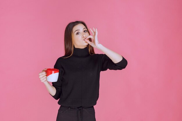 Femme en pull noir prenant un café et appréciant le goût.