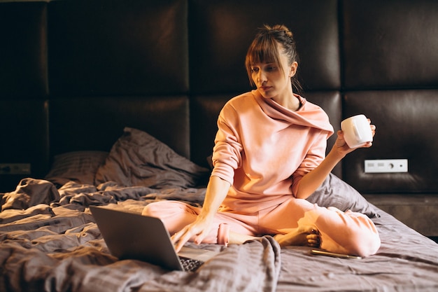 Femme en pygama travaillant sur un ordinateur portable au lit