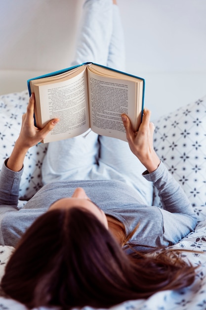 Femme en pyjama lisant sur le lit