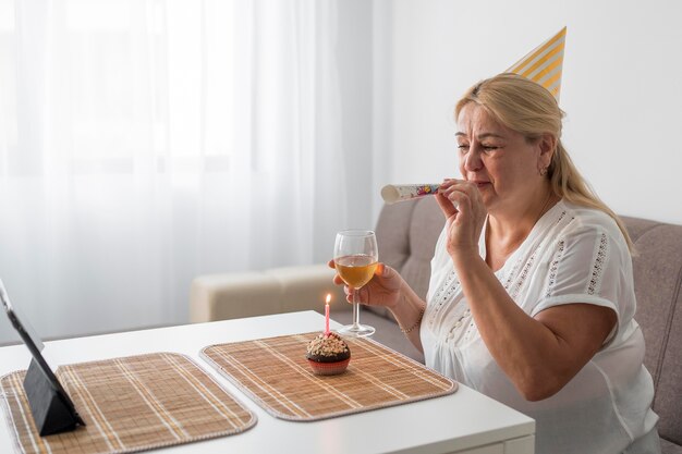 Femme en quarantaine célébrant son anniversaire avec boisson et ordinateur portable