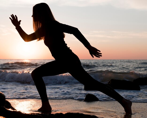 Femme qui court sur la plage au coucher du soleil