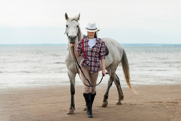 Femme qui marche avec un cheval sur la plage