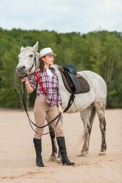 Femme qui marche avec un cheval sur la plage