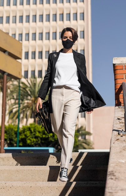 Femme qui marche dans la ville tout en portant un masque médical