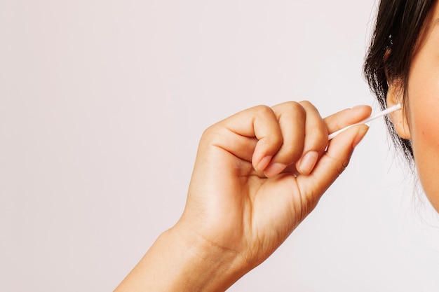 Femme qui nettoie ses oreilles avec des écouvillons en coton