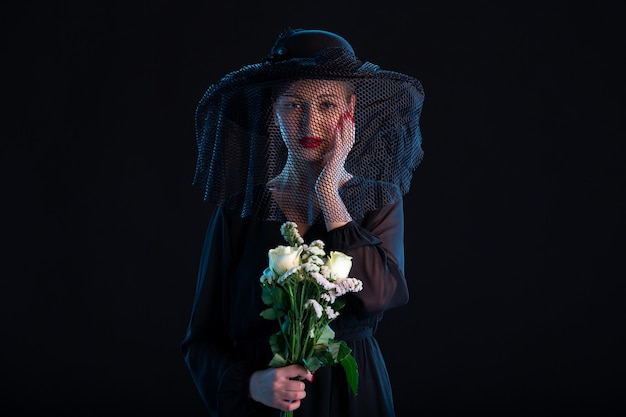 Femme qui pleure vêtue de noir avec des fleurs sur les funérailles de la tristesse de la mort noire