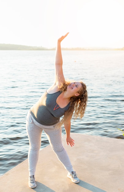 Photo gratuite femme qui s'étend au bord du lac