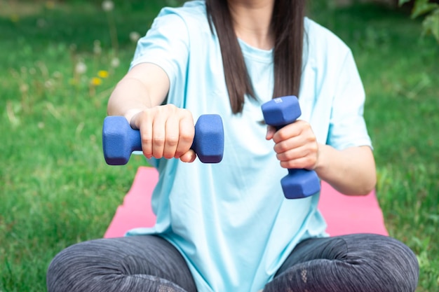 Photo gratuite femme qui s'étend avec des haltères faisant des exercices de fitness dans un parc verdoyant