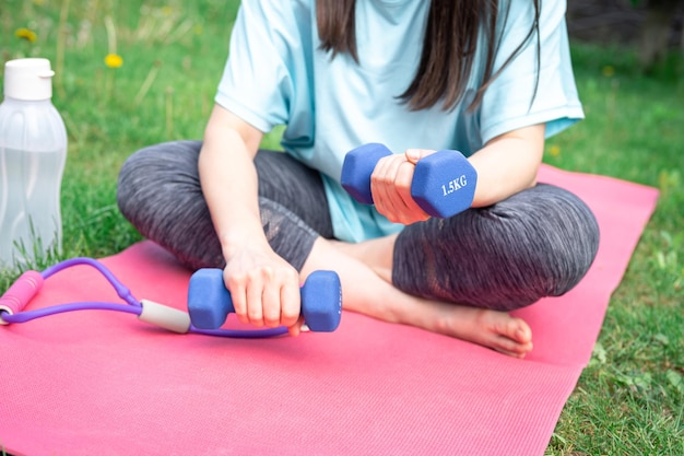 Photo gratuite femme qui s'étend avec des haltères faisant des exercices de fitness dans un parc verdoyant