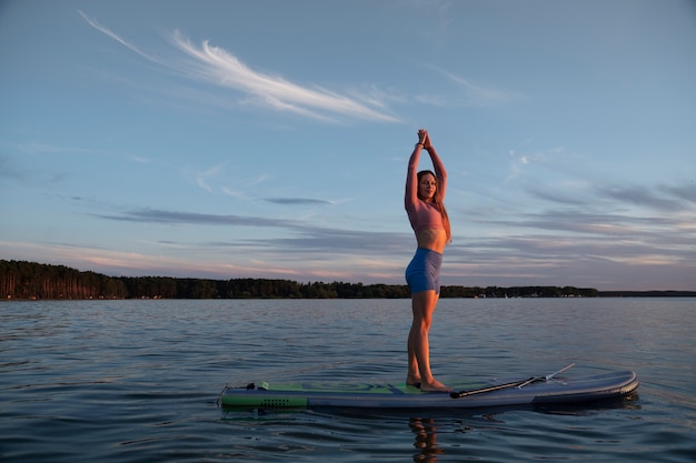 Femme qui s'étend sur le paddleboard full shot