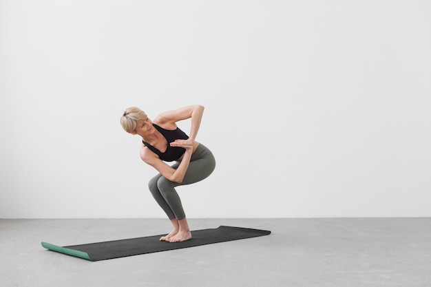 Femme qui s'étend sur un tapis de yoga