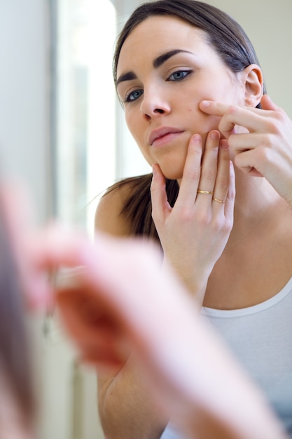 Femme qui s&#39;occupe de sa belle peau sur le visage debout près de mir