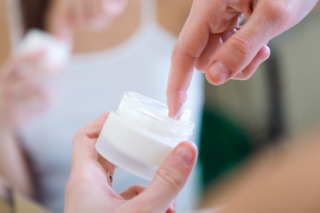 Femme qui s&#39;occupe de sa peau debout près du miroir dans la salle de bain.