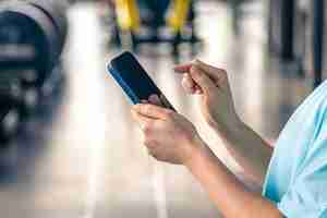 Photo gratuite une femme qui utilise un smartphone dans un gymnase en gros plan