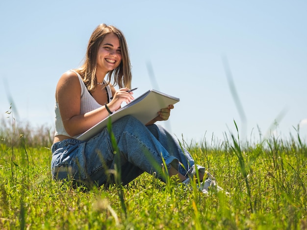 Femme de race blanche assise et dessin dans la nature