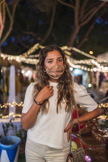 Femme de race blanche bronzée portant un masque floral dans un parc d'attractions