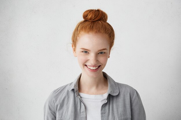 Femme de race blanche avec chignon de cheveux roux à la recherche de ses yeux charmants bleus démontrant son sourire sincère. Jolie femme rousse naturelle étant heureuse