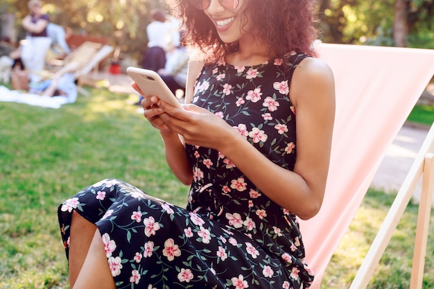 Photo gratuite femme de race mixte aux cheveux bouclés se détendre dans le parc d'été en week-end ensoleillé