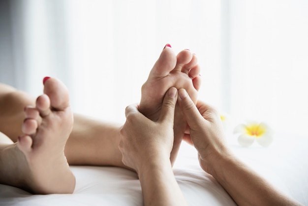 Femme recevant un service de massage des pieds de la masseuse se bouchent les pieds et les mains - concept de service de massage