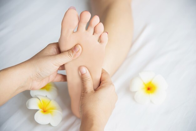 Femme recevant un service de massage des pieds de la masseuse se bouchent les pieds et les mains - concept de service de massage
