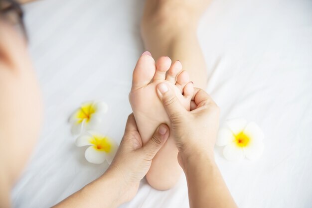 Femme recevant un service de massage des pieds de la masseuse se bouchent les pieds et les mains - concept de service de massage