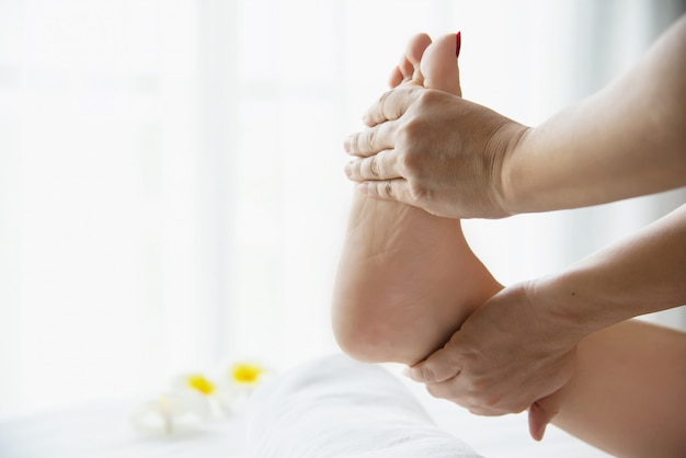 Femme recevant un service de massage des pieds de la masseuse se bouchent les pieds et les mains - concept de service de massage