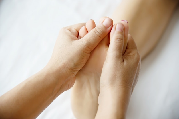 Femme recevant un service de massage des pieds de la masseuse se bouchent les pieds et les mains - concept de service de massage