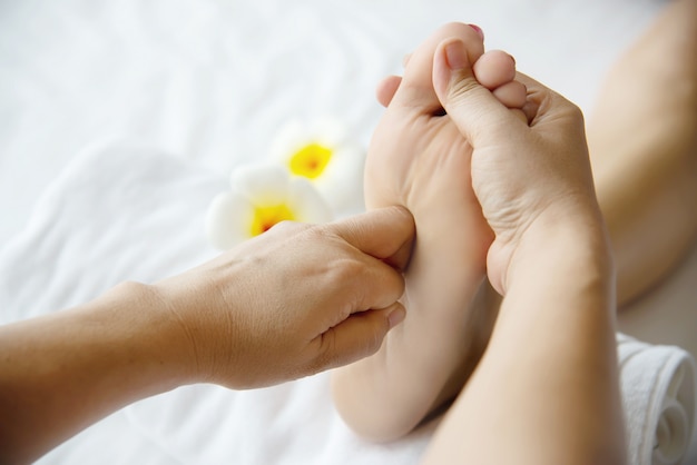 Femme recevant un service de massage des pieds de la masseuse se bouchent les pieds et les mains - concept de service de massage
