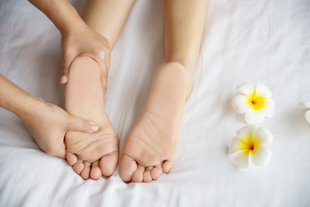 Femme recevant un service de massage des pieds de la masseuse se bouchent les pieds et les mains - concept de service de massage