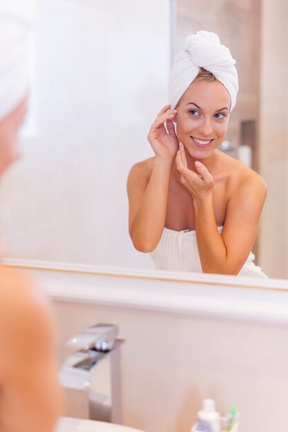 Femme à la recherche d'elle-même reflet dans le miroir après la douche