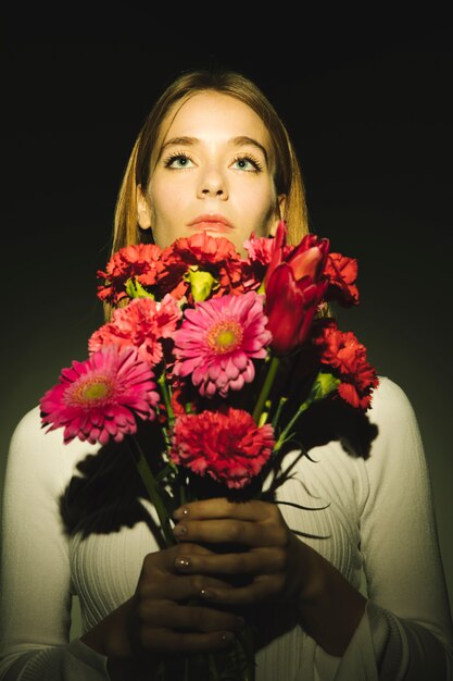 Femme réfléchie avec bouquet de fleurs aux couleurs vives