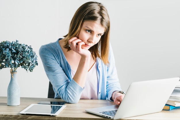 Femme réfléchie, navigation sur ordinateur portable au bureau